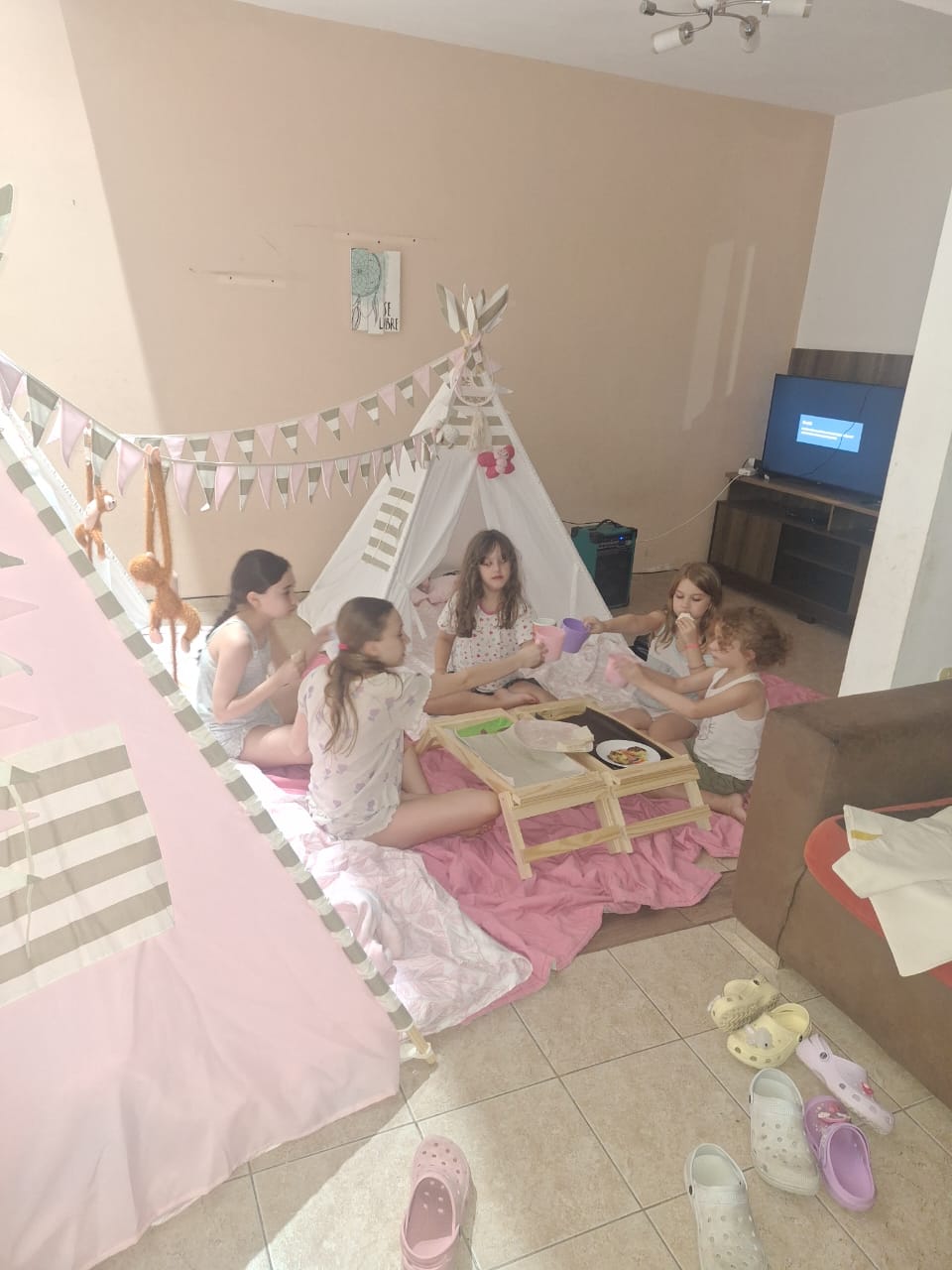 Grupo de nenas disfrutando de una merienda entre carpas tipi decoradas