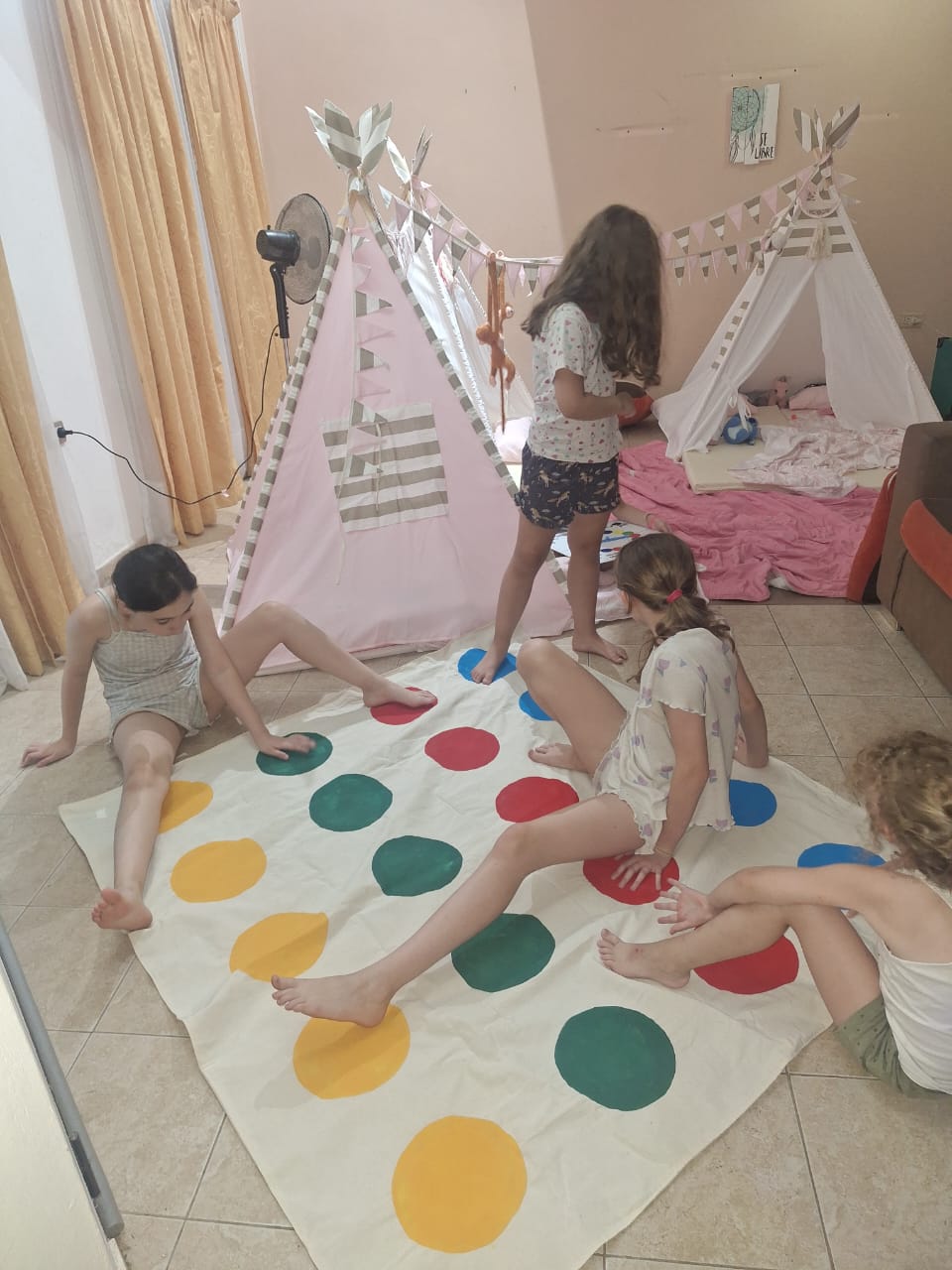 Nenas jugando Twister gigante entre carpas tipi con banderines